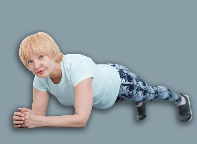 Senior woman in sportswear doing plank exercise at home