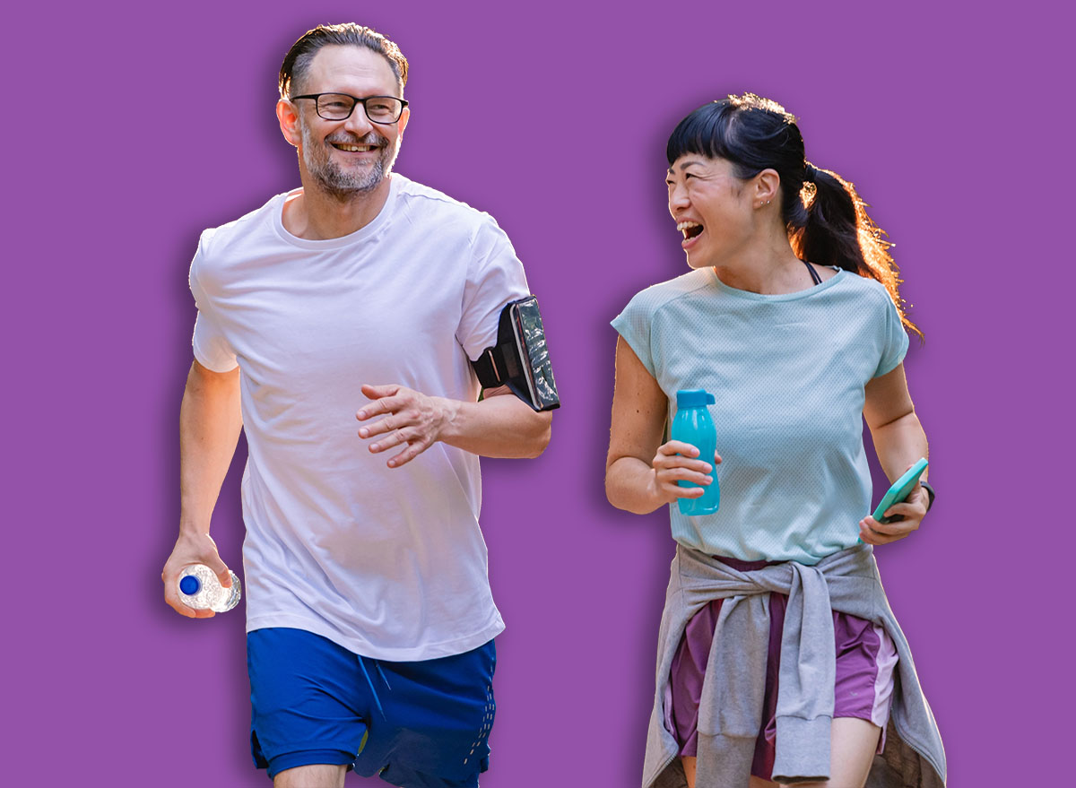 Happy diverse middle-aged couple jogging together in park, smiling and talking while exercising outdoors, enjoying active lifestyle, health, and fitness in nature
