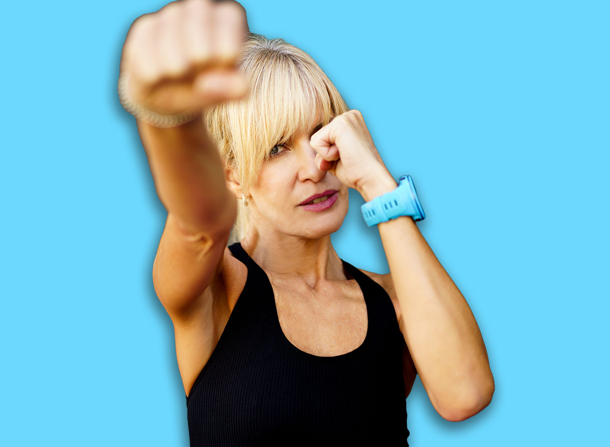 Strong female fighter performing martial art punch in fitness club