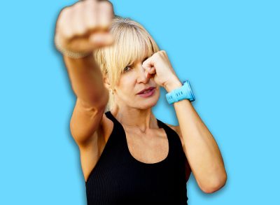 Strong female fighter performing martial art punch in fitness club