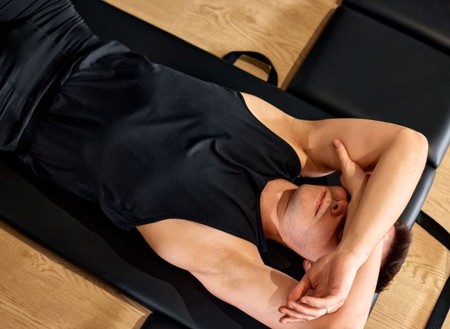 Person resting on an exercise mat after a workout session in the gym