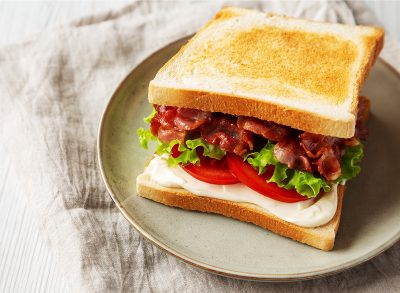 Homemade BLT Sandwich (Bacon, Lettuce and Tomato) on a Plate, side view. Copy space.