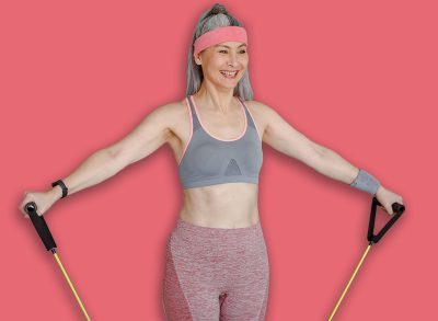 Joyful female sportswoman using resistance pull rope while having strength workout at home