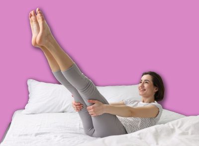 Young woman exercising on bed at home. Morning routine