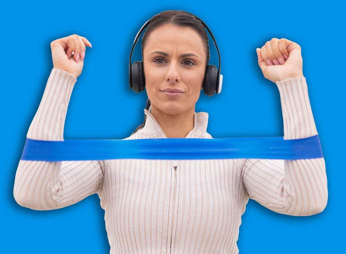 Woman performing resistance band exercise with headphones on a bridge
