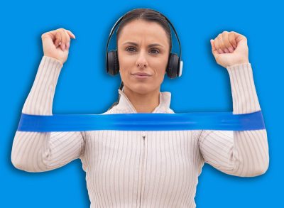 Woman performing resistance band exercise with headphones on a bridge