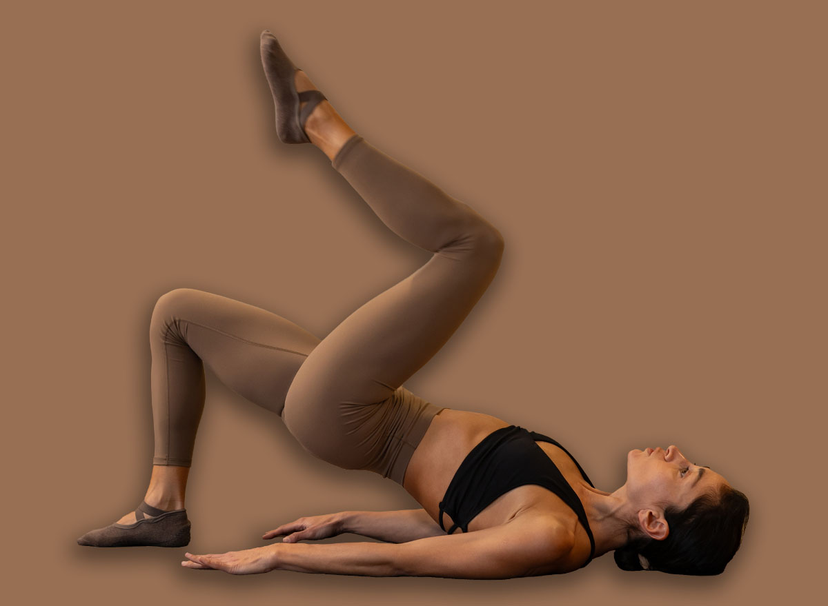 Athletic woman performing pilates single leg bridge exercise foc