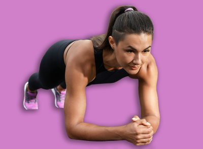 Young woman doing plank exercise on grass in park