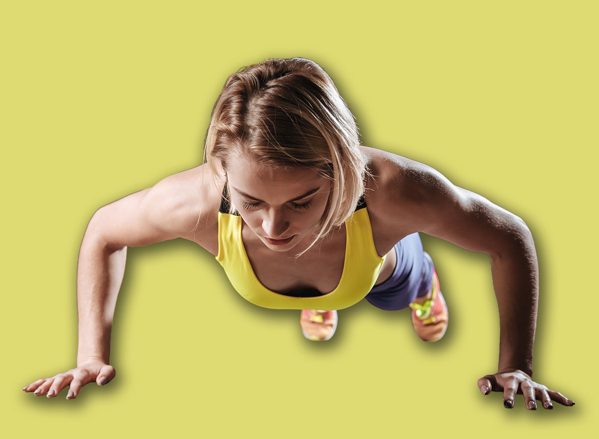 Beautiful young athletic woman making push-up exercises in gym.