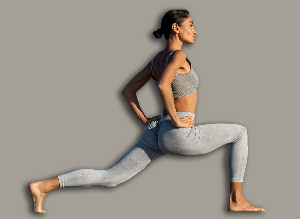 Athletic woman practicing yoga lunge pose outdoors on a sunny da