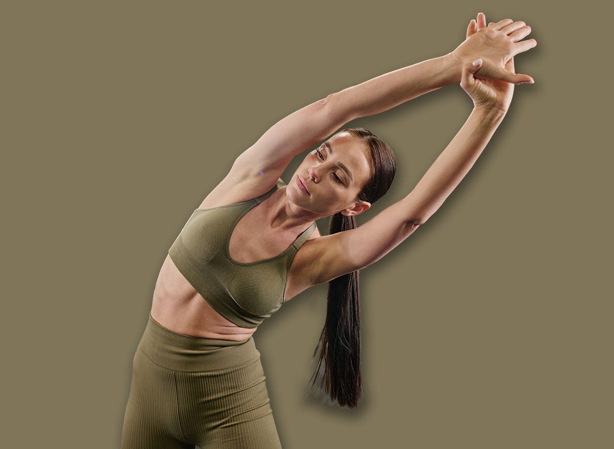 Toned brunette woman dressed in sportswear doing side bendings to develop flexibility