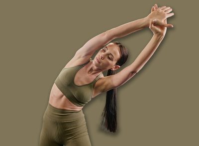 Toned brunette woman dressed in sportswear doing side bendings to develop flexibility