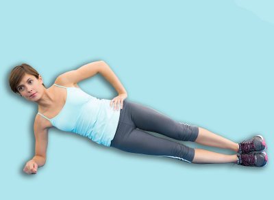 Fit brunette doing pilates on exercise mat at the gym
