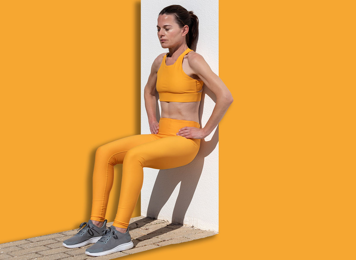 Fit woman doing squat exercise against a wall
