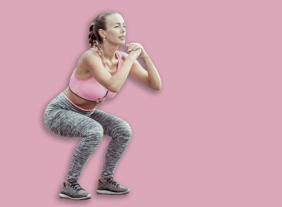 Fit woman crouches outdoors. Active lifestyle. Practicing squats