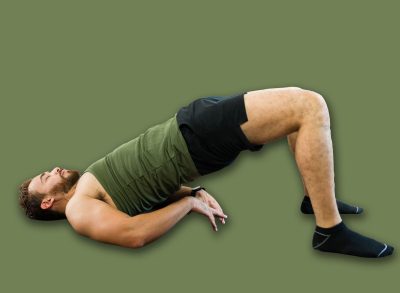 Fit young man is doing a bridge exercise on a mat at home to strengthen his body and improve his physical condition
