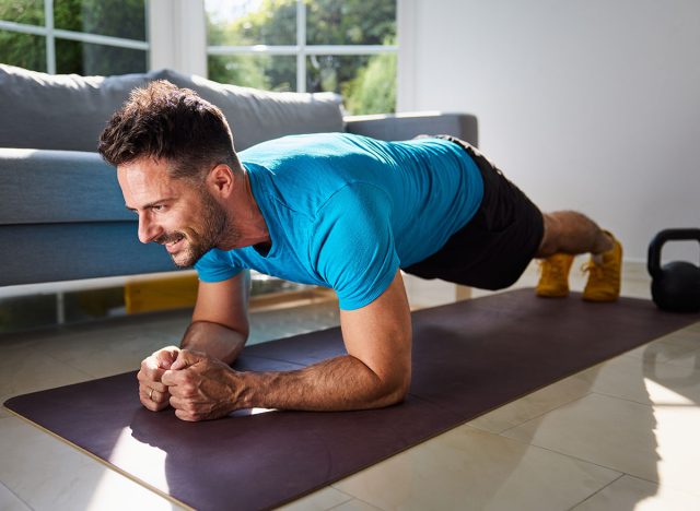 Adult man at home doing plank exercise