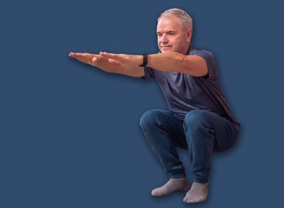 Senior man doing home workout squat exercise on yoga mat in living room