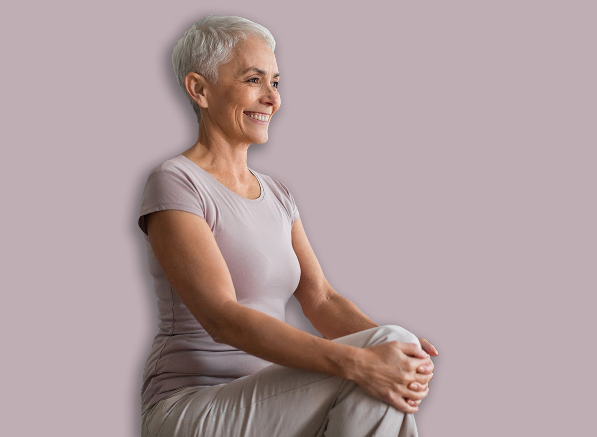 Cardio Workout. Cheerful Mature Woman Doing High Knees Exercise, Warming Up During Training In Living Room, Standing And Lifting Leg Up To Chest, Stretching Hamstring Muscles