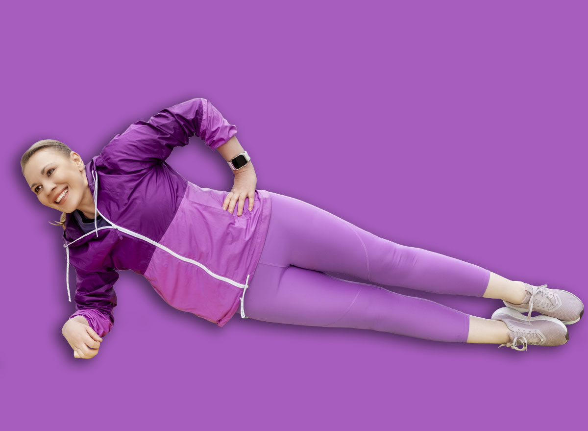 Woman performing side plank exercise on yoga mat in city park, purple sportswear, strength and balance training, outdoor fitness routine, healthy lifestyle concept