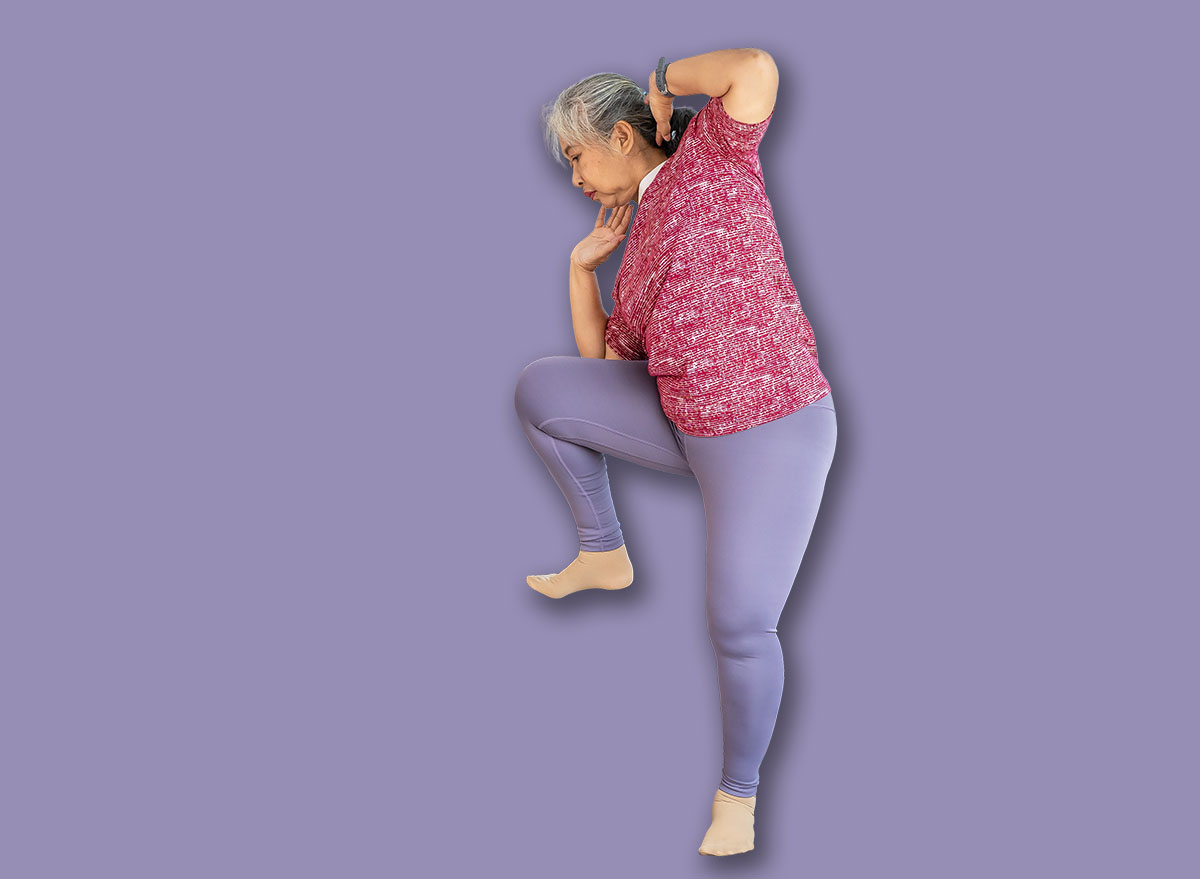 Senior woman exercise with standing oblique crunch or side crunch, she watch training online in tablet during workout