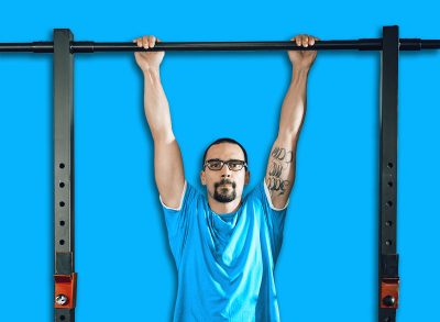 Handsome young muscular man doing pull-ups exercise at the gym. Looking at camera.