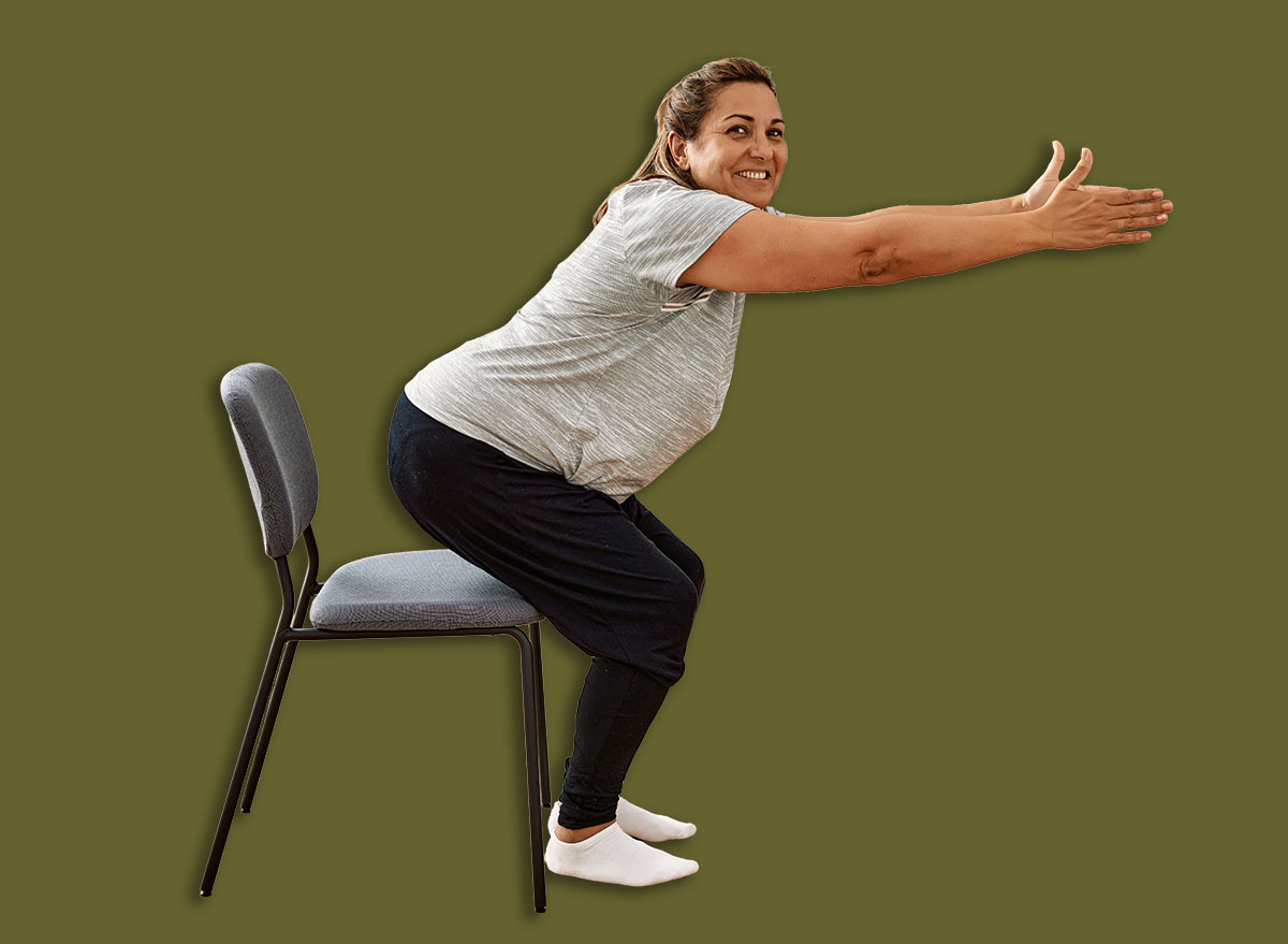 Middle age hispanic couple stretching using chair at sport center.