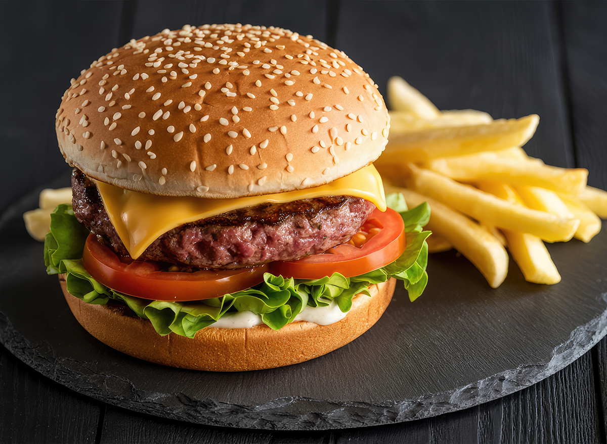 Delicious hamburger with cheese and french fries on a dark slate plate