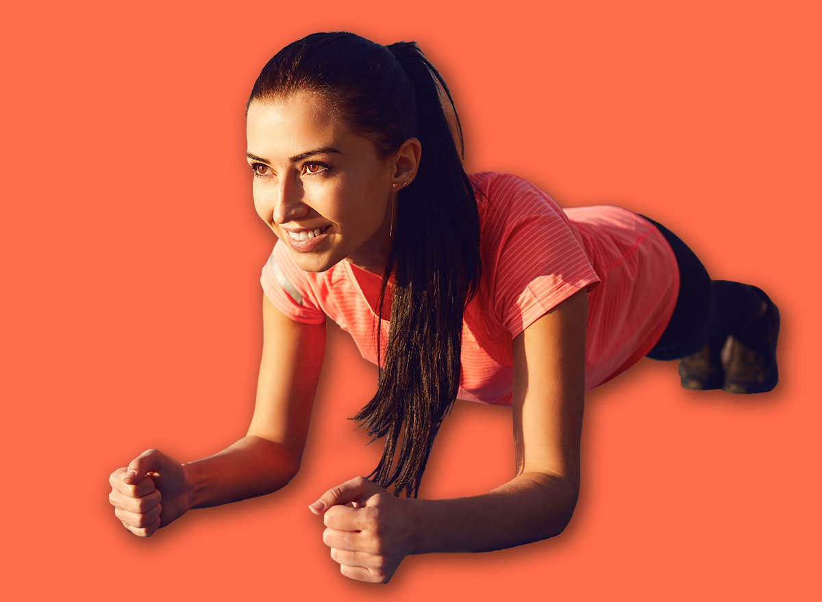 Girl does a plank exercise by the lake on nature