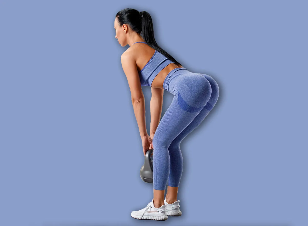 Fitness woman doing deadlift exercise for glutes on gray background. Athletic girl working out with kettlebell