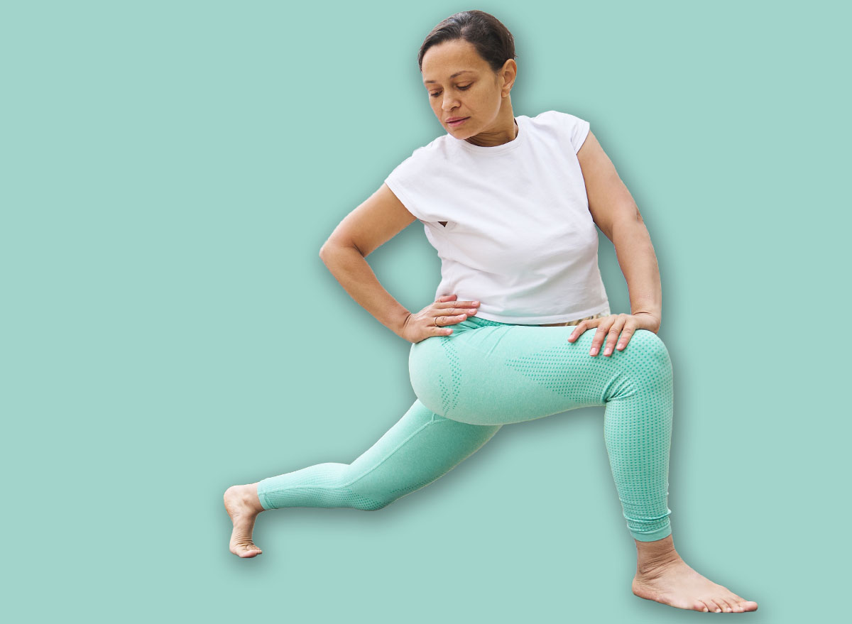 A woman in activewear performs yoga stretches on an outdoor deck, surrounded by greenery, promoting relaxation and wellness.