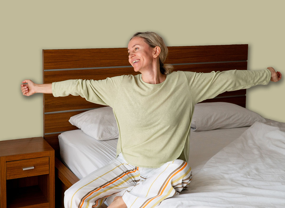 Happy Refreshed Woman waking up from Bed in the Morning by Stretching hands - concept of positive emotion, rejuvenation and relaxation