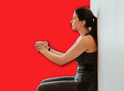 Sporty woman doing squats against a wall