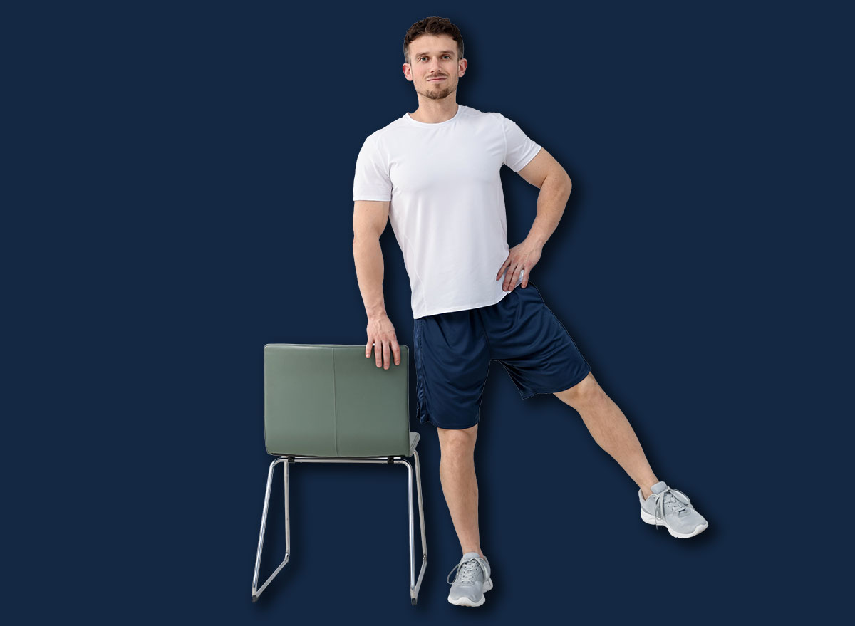 Handsome man exercising with chair at home