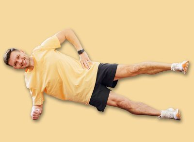 Man exercising on living room floor with relaxed posture and colorful rug during daytime