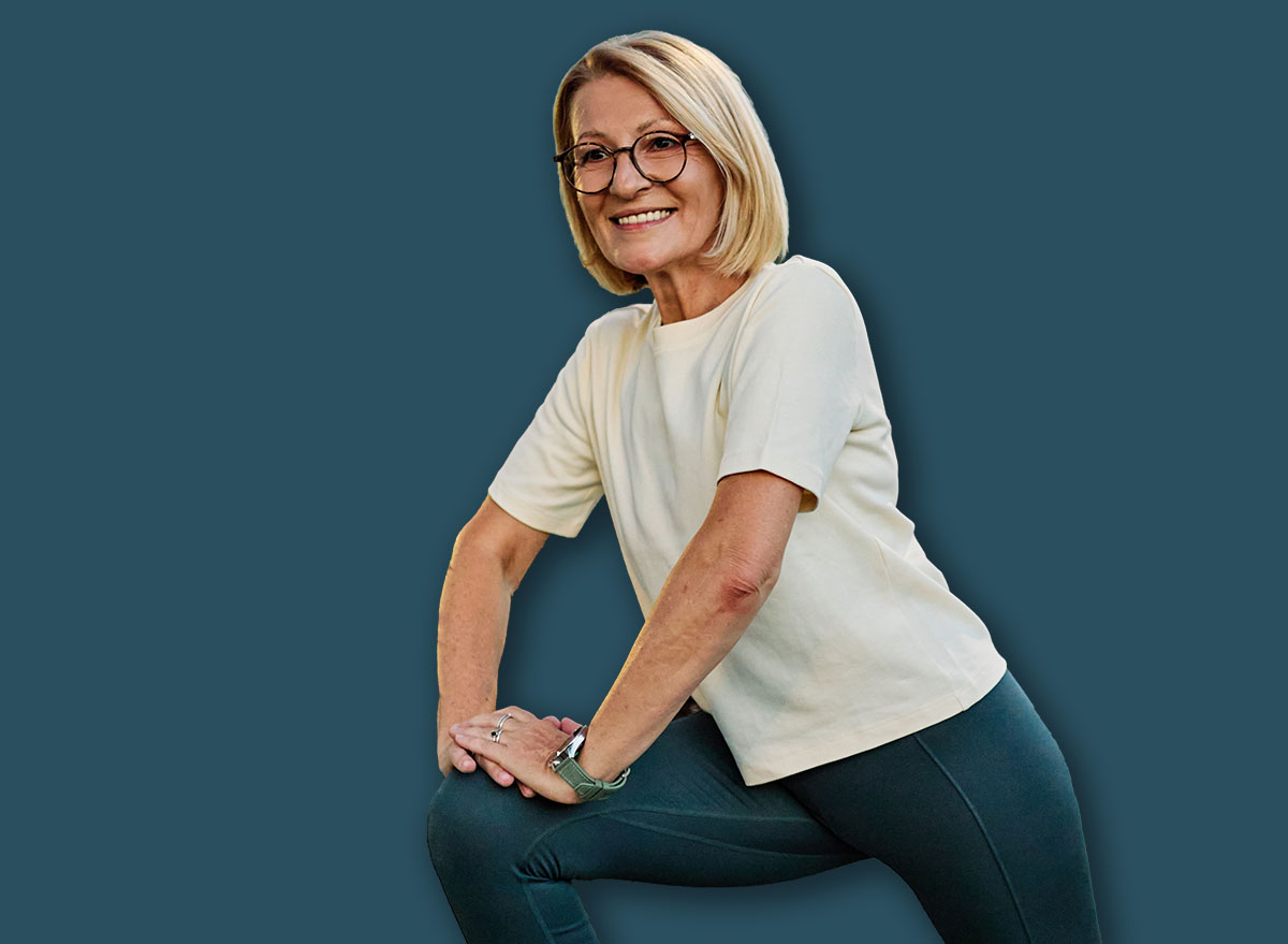 Portrait of a middle aged mature beautiful sport woman smiling happy and confident. Standing and doing exercise and stretching in city park outdoors