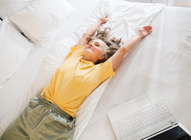 elderly woman lying on a bed in the bedroom. rest from gadgets. healthy seniors lifestyle.