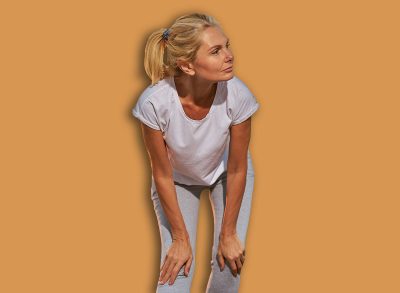 Ruminative mature Caucasian female in sportswear with her hands resting on the slightly bent knees
