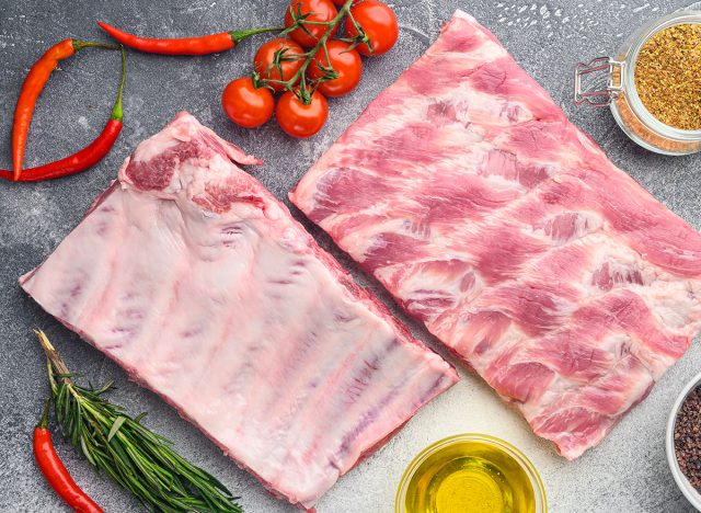 Raw ribs with a rosemary and vegetables set, on gray background, top view flat lay