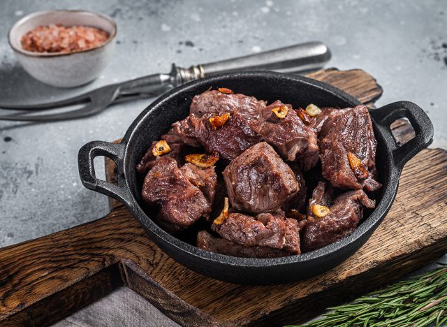 Grilled Sauteed Diced Beef in a skillet with garlic. Gray background. Top view.