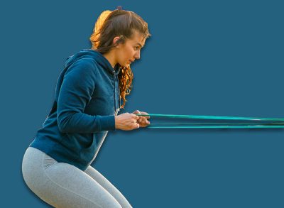 A smiling woman with curves exercises in the park with resistance bands.