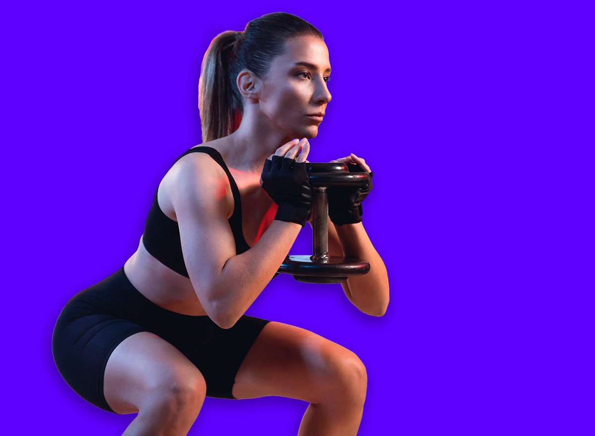 One woman doing goblet squat exercise in a gym with a dumbbell