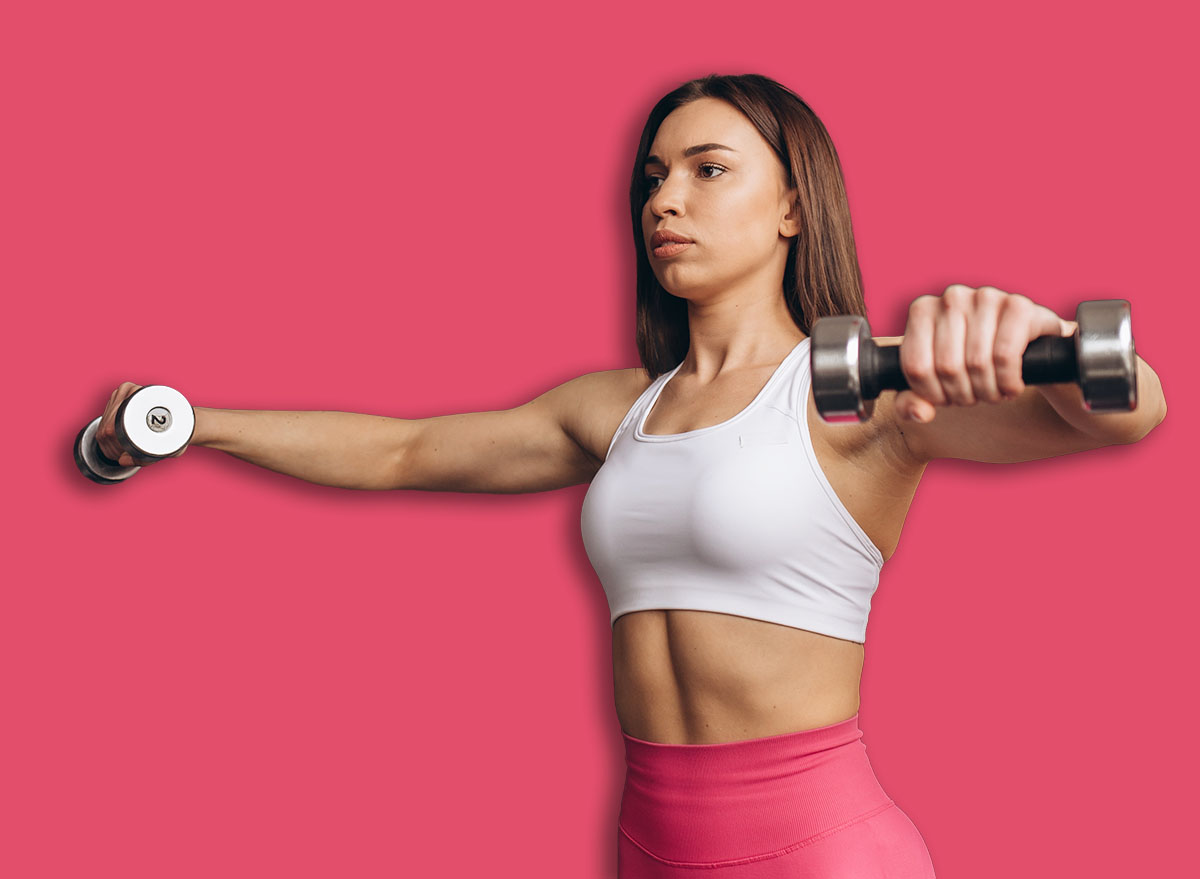 Reaching her goals. Attractive young fit and toned sportswoman doing lateral raises smiling confidently working out with dumbbells at the gym copyspace motivation confidence success competitive smile