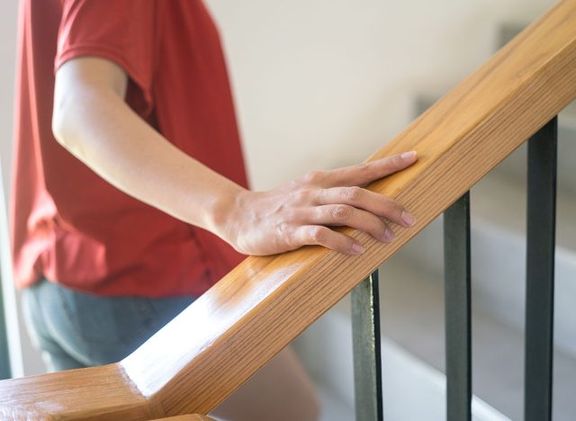 Close-up at woman hand is holding on the stairway handrail during walking up the stair. People in action photo, selective focus.