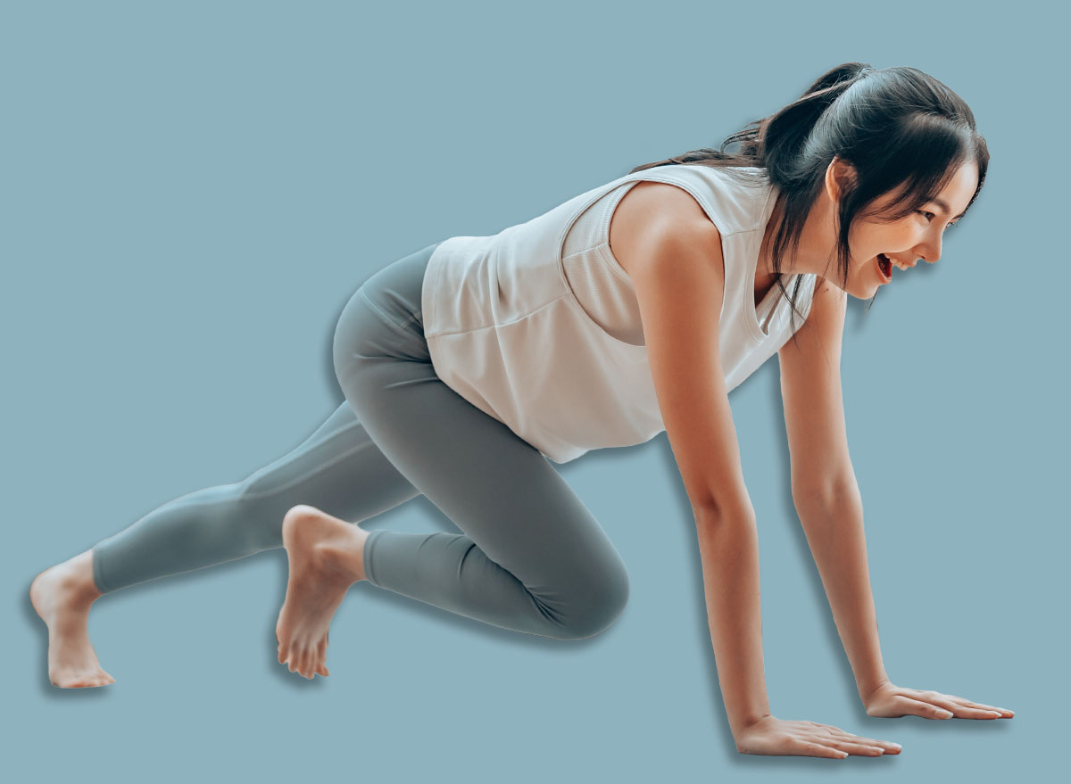Young Asian woman doing sport exercises indoor. Beautiful girl workout at home. Athletic outfit is doing mountain climber exercises