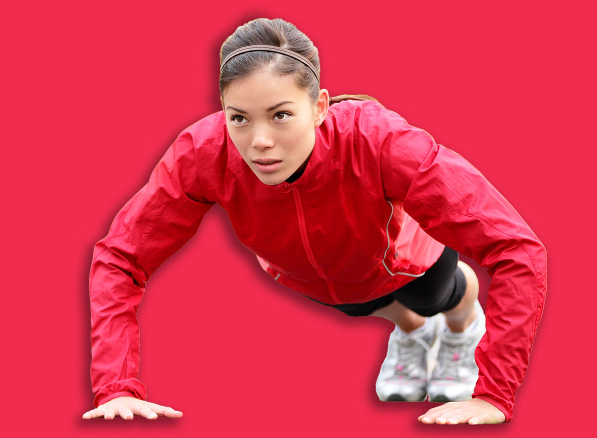 Fitness woman doing push-ups during outdoor cross training workout. Beautiful young and fit fitness sport model training outside in fall.