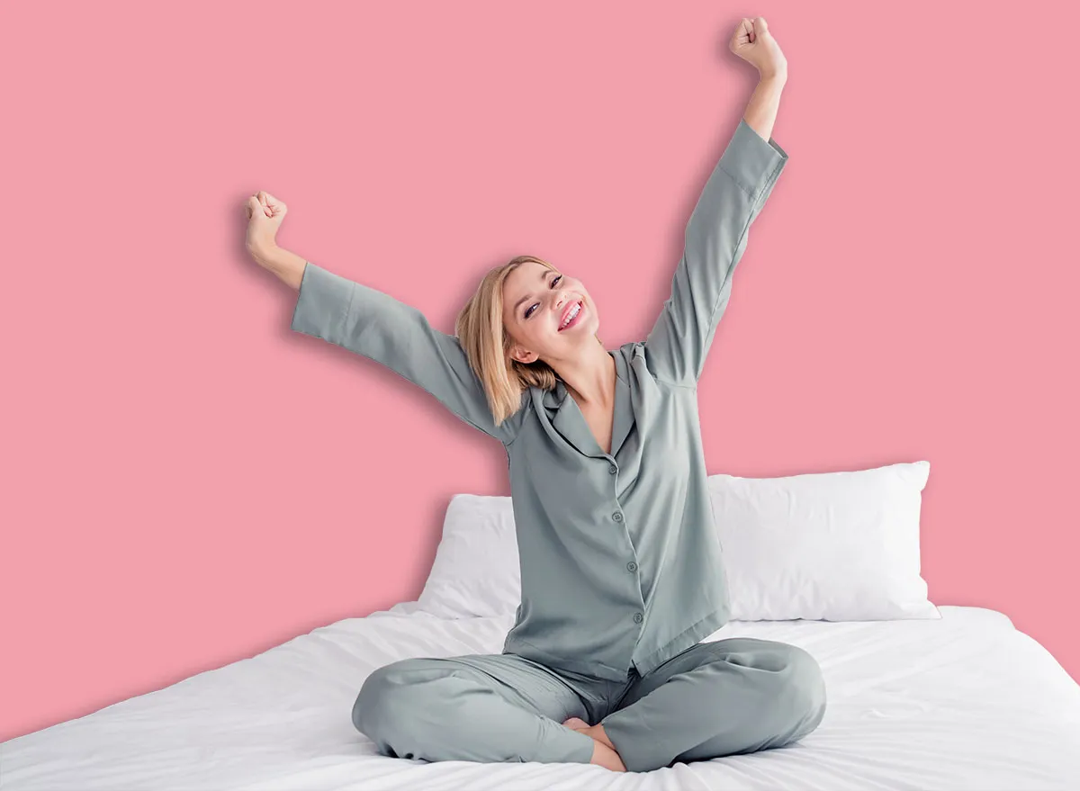 Full length body photo of young blonde girl in cozy grey victoria secret brand pajama wake up morning raised fists yawning indoors