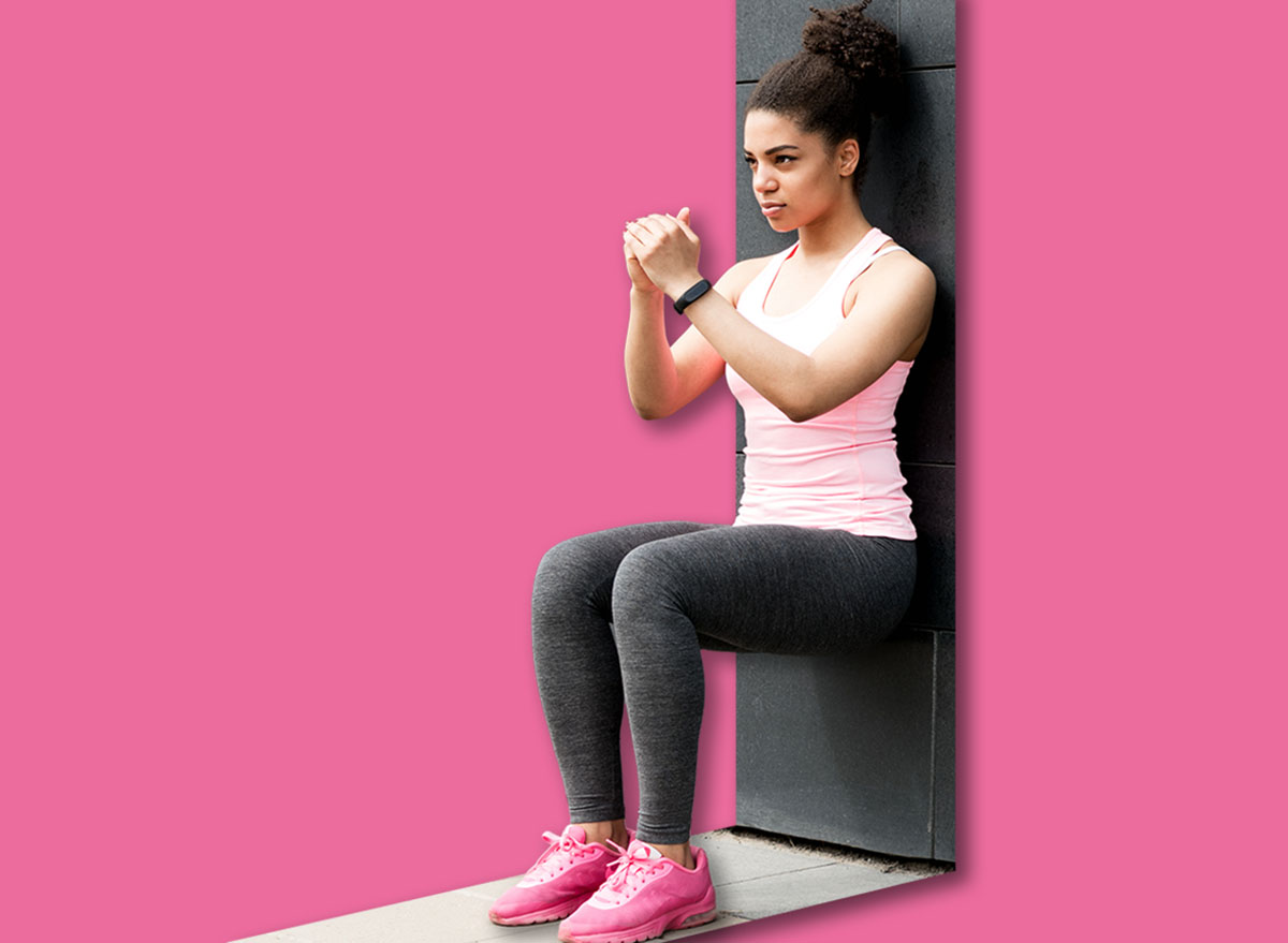 Athlete doing wall squat on city street
