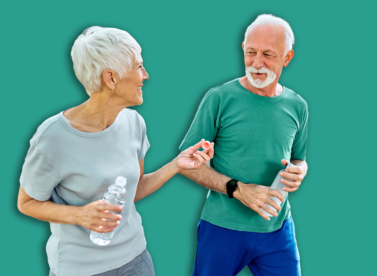 Smiling active senior couple jogging exercising and having fun and laughing together taking and walking a break in the park