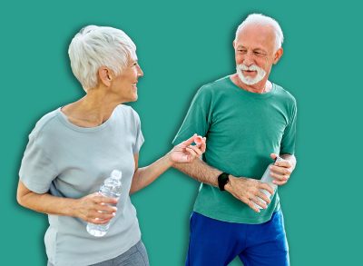 Smiling active senior couple jogging exercising and having fun and laughing together taking and walking a break in the park